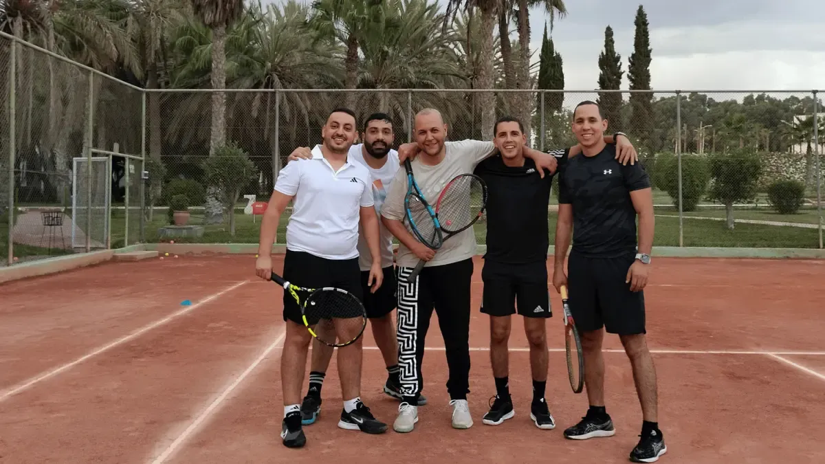 École de tennis adultes : cinq joueurs du club, raquettes à la main, sur un court en terre battue