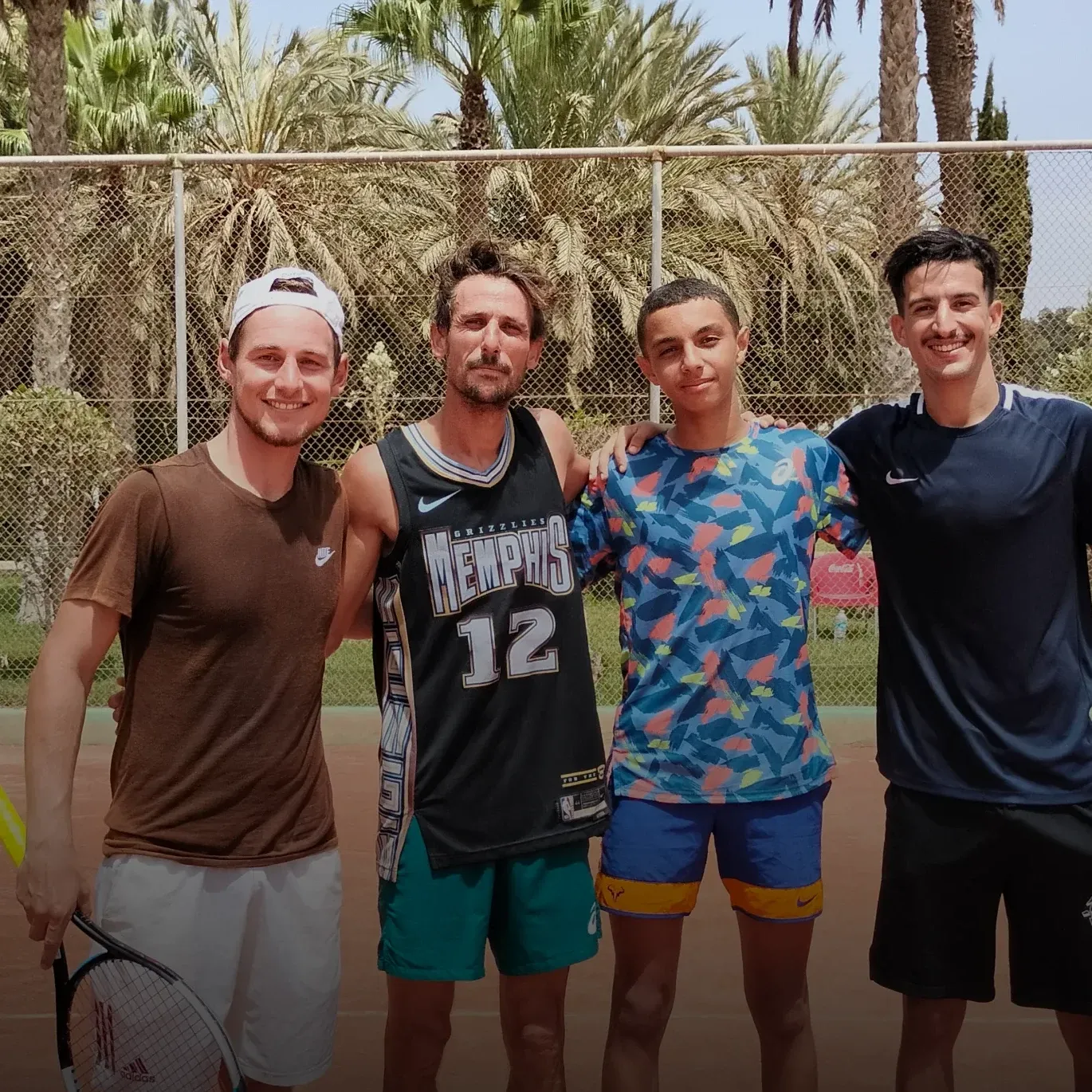 Stage de tennis pour adultes à Agadir : quatre stagiaires réunis sur la terre battue du club après une séance