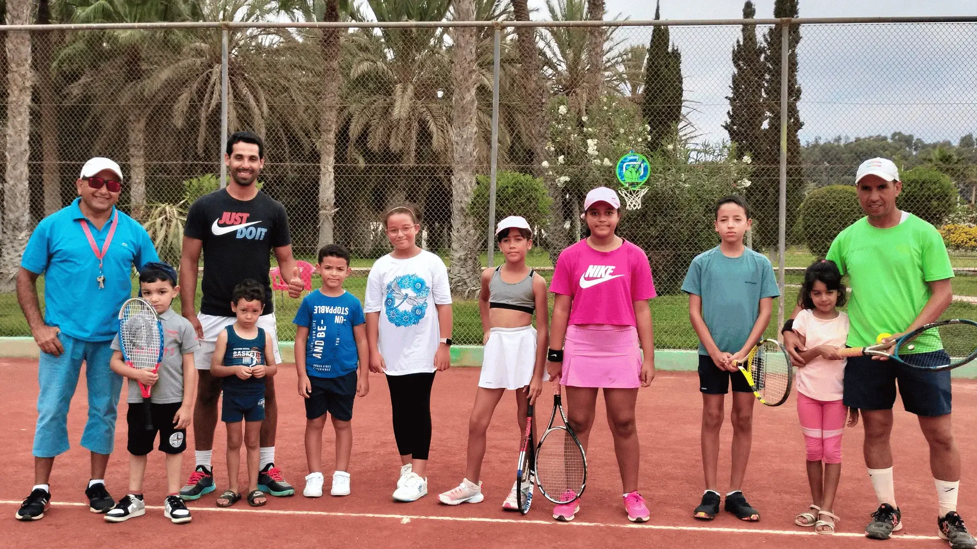 Les jeunes de l'école de tennis et leurs coachs, alignés sur la terre battue du club